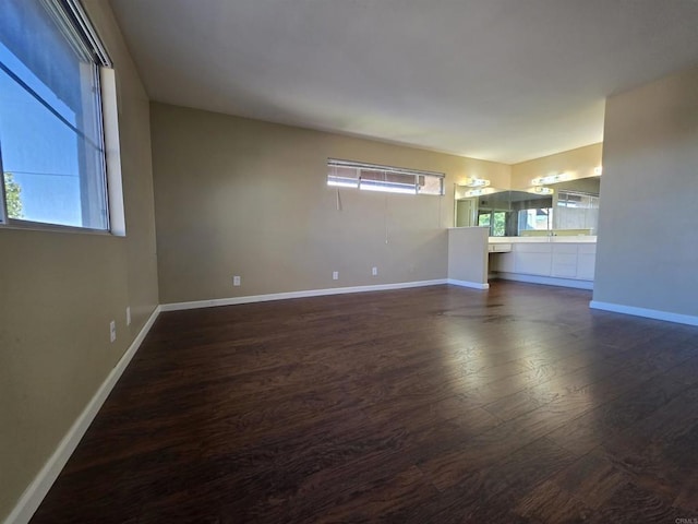 unfurnished room with dark wood-style floors, a wealth of natural light, and baseboards