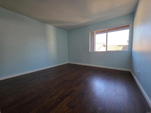 spare room with dark wood-style flooring and baseboards