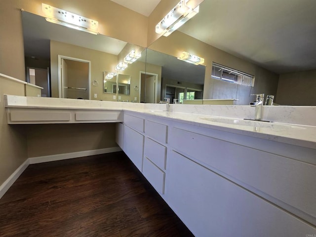 bathroom featuring double vanity, baseboards, a sink, and wood finished floors