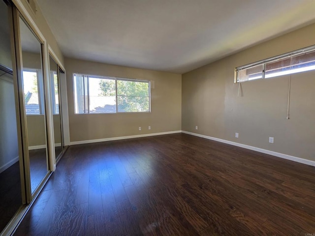 spare room featuring dark wood-style flooring and baseboards