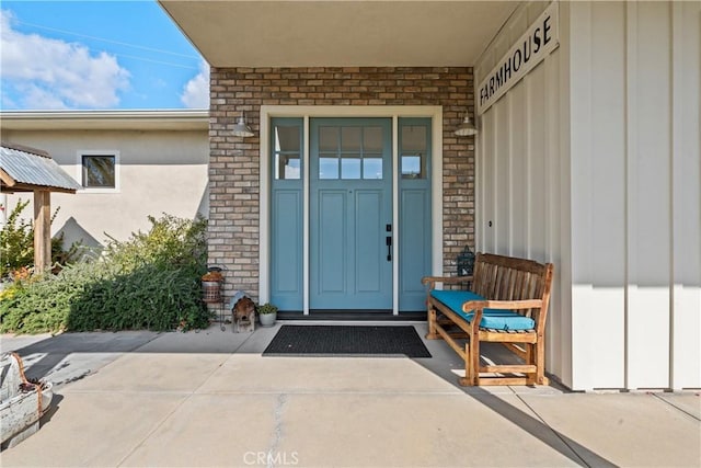 entrance to property featuring board and batten siding and brick siding