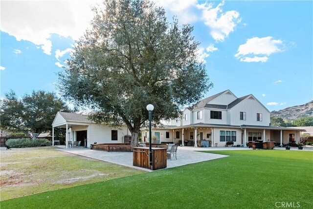 back of property with outdoor dry bar, a lawn, and a patio