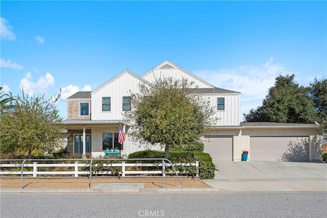 view of front facade featuring driveway, a fenced front yard, an attached garage, and board and batten siding