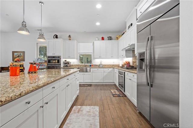 kitchen featuring white cabinetry, hardwood / wood-style flooring, stainless steel appliances, sink, and pendant lighting