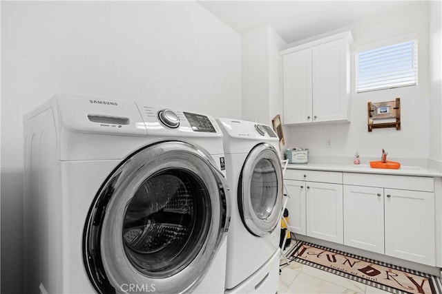 laundry area featuring sink, washer and clothes dryer, and cabinets