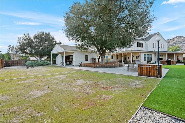 rear view of house with a patio, fence, a lawn, and outdoor dry bar