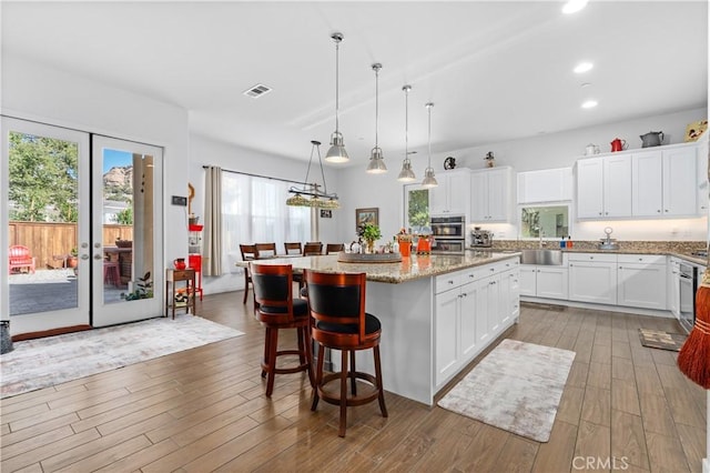 kitchen featuring a center island, white cabinetry, and decorative light fixtures