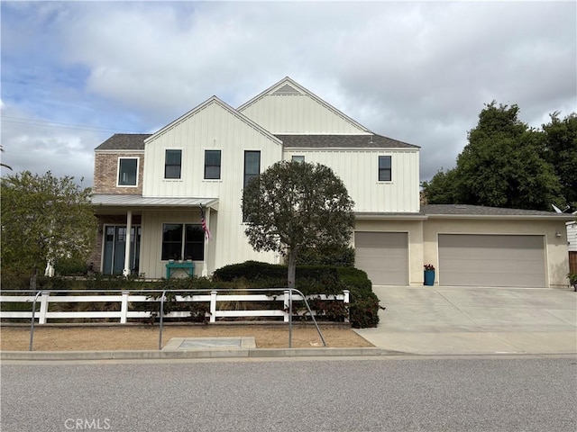 view of front of house with concrete driveway, board and batten siding, a fenced front yard, a garage, and a shingled roof