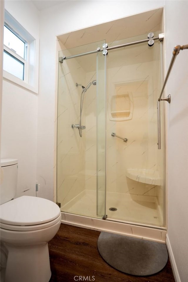 bathroom featuring toilet, a shower with door, and hardwood / wood-style floors