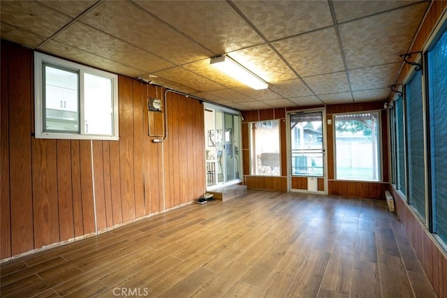 empty room with wood walls, hardwood / wood-style floors, and a wealth of natural light