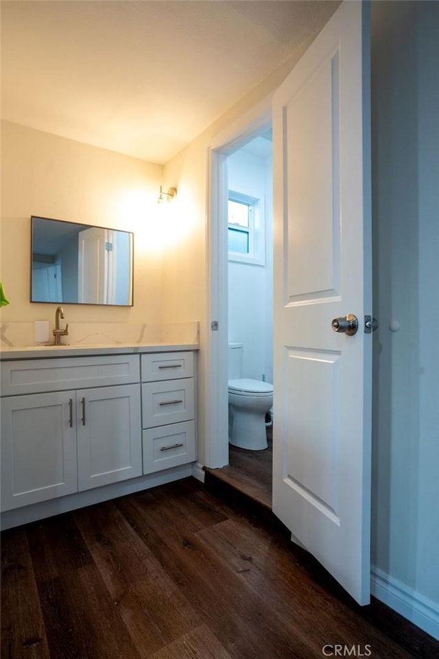 bathroom featuring wood-type flooring, toilet, and vanity