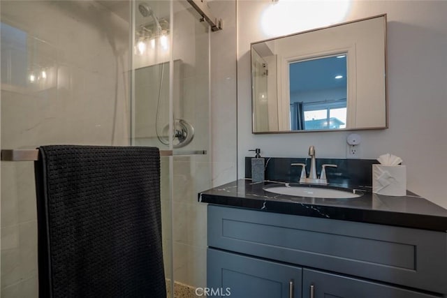 bathroom featuring a shower with door and vanity