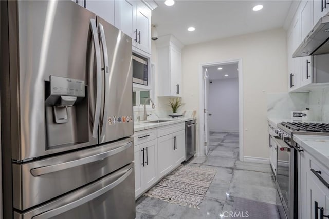 kitchen with white cabinetry, light stone countertops, stainless steel appliances, and sink