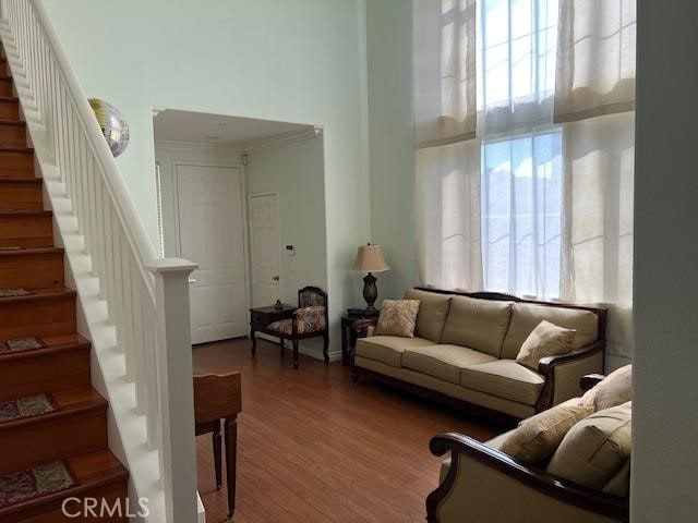 living area with stairway, a high ceiling, and wood finished floors