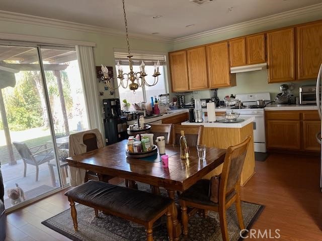 kitchen with light countertops, ornamental molding, light wood-type flooring, white range with gas stovetop, and under cabinet range hood