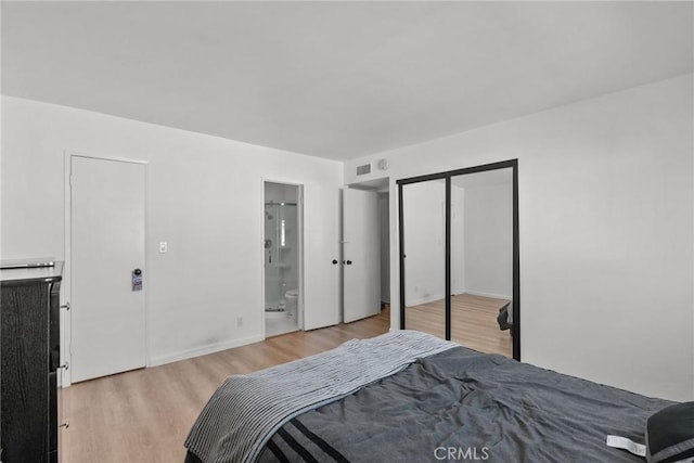 bedroom featuring a closet, ensuite bathroom, and light hardwood / wood-style flooring