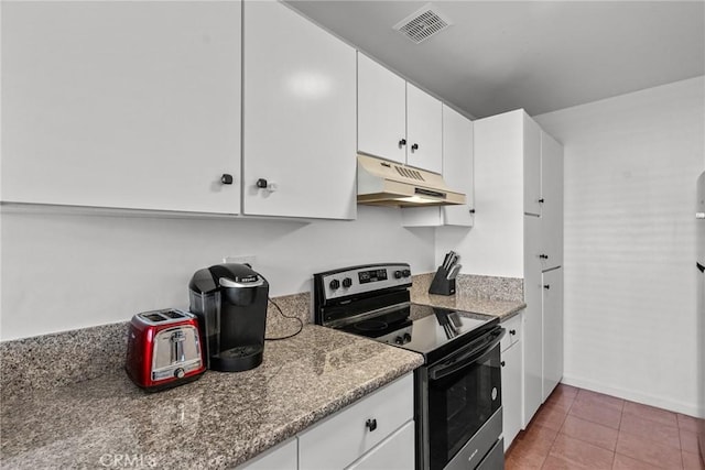 kitchen featuring tile patterned floors, dark stone counters, stainless steel electric range, and white cabinets