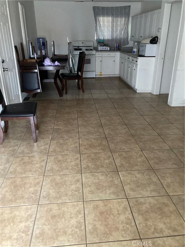 kitchen featuring white appliances, tile patterned flooring, and white cabinets