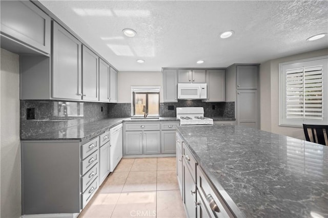 kitchen with light tile patterned flooring, sink, gray cabinetry, white appliances, and decorative backsplash