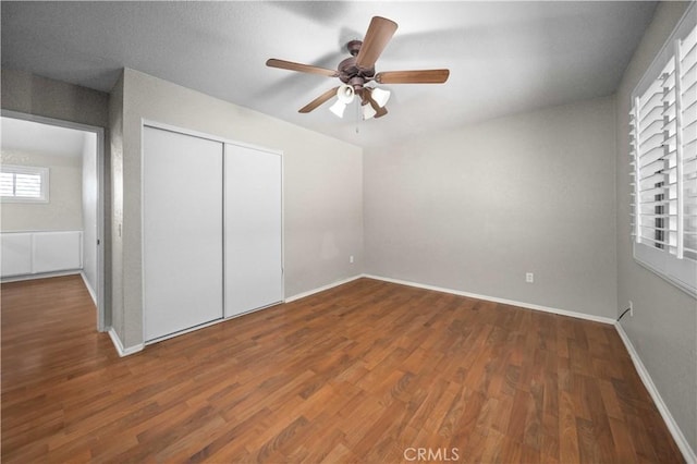 unfurnished bedroom with dark wood-type flooring, ceiling fan, and a closet