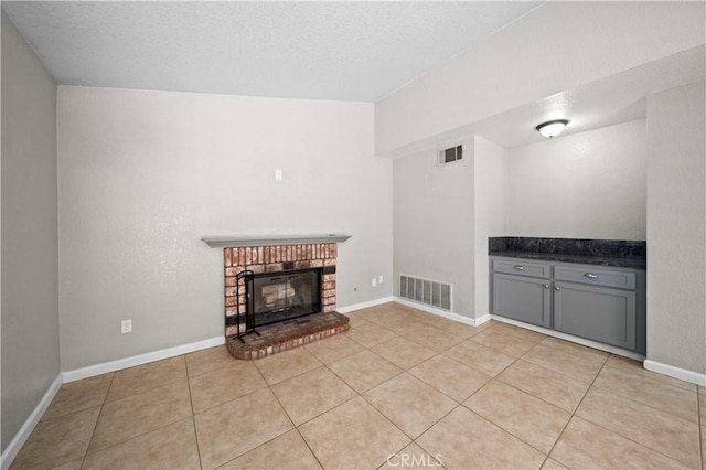 unfurnished living room with a fireplace, a textured ceiling, and light tile patterned flooring