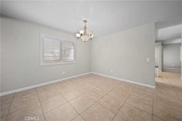 tiled empty room featuring an inviting chandelier