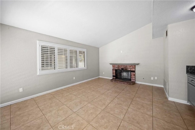 unfurnished living room with light tile patterned flooring, vaulted ceiling, and a brick fireplace