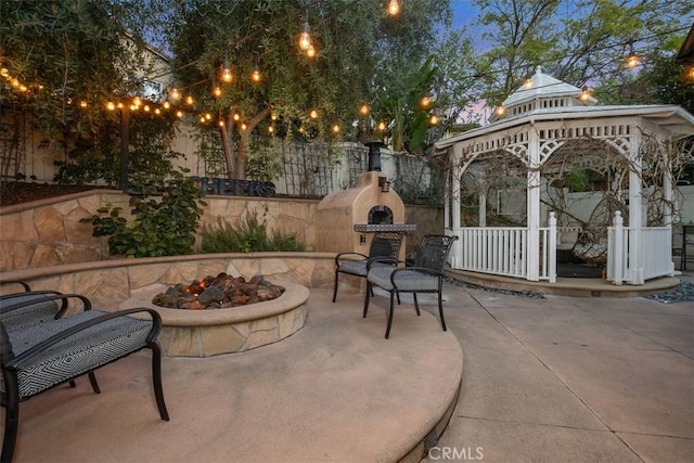 view of patio featuring a gazebo, an outdoor fire pit, and an outdoor stone fireplace