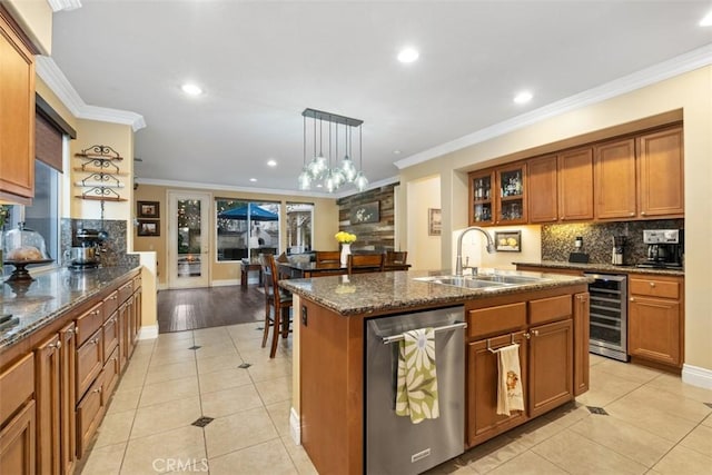 kitchen with sink, dishwasher, hanging light fixtures, an island with sink, and beverage cooler