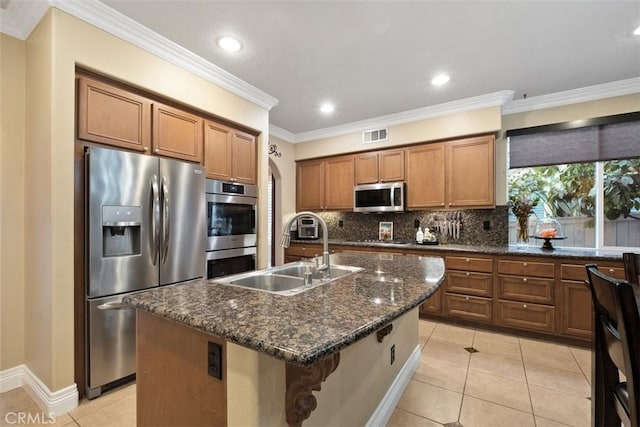 kitchen with stainless steel appliances, sink, dark stone countertops, and a kitchen island with sink