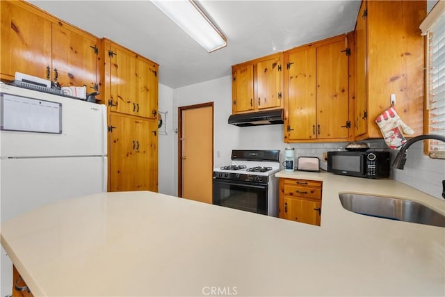 kitchen with sink, decorative backsplash, white appliances, and kitchen peninsula