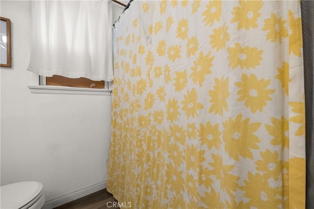 bathroom featuring hardwood / wood-style flooring, curtained shower, and toilet