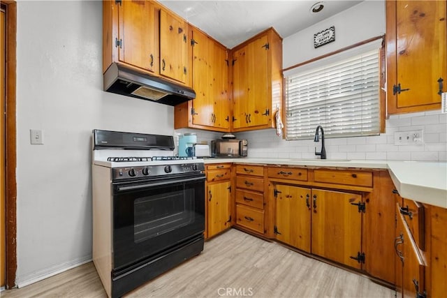 kitchen featuring gas stove, sink, backsplash, and light hardwood / wood-style floors