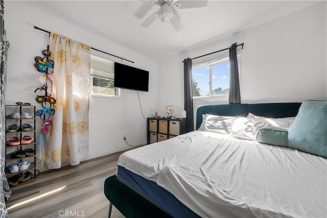 bedroom featuring ceiling fan, hardwood / wood-style floors, and multiple windows