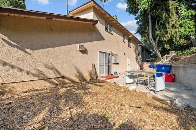 back of house with a wall unit AC and a patio