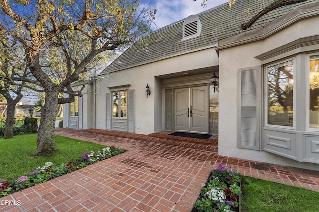 entrance to property featuring a patio and a lawn