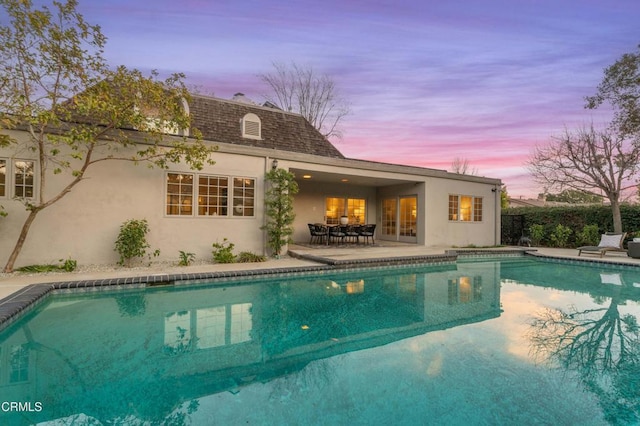 pool at dusk featuring a patio area