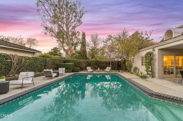 pool at dusk featuring a patio area