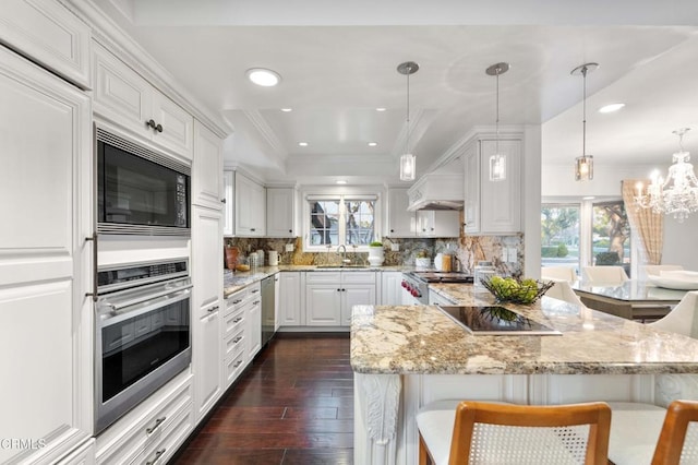 kitchen featuring pendant lighting, black appliances, a kitchen breakfast bar, and white cabinets