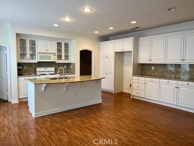 kitchen with white microwave, glass insert cabinets, dark wood-type flooring, white cabinetry, and range