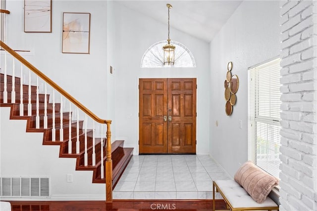 tiled entrance foyer featuring a wealth of natural light and high vaulted ceiling