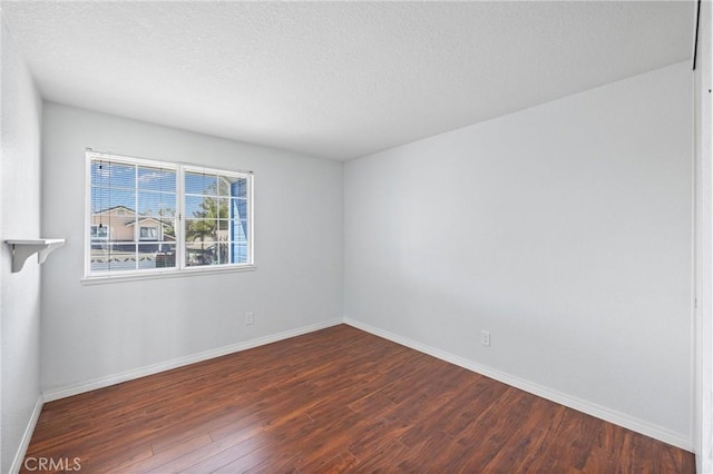 empty room featuring dark wood-type flooring and a textured ceiling