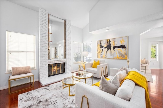 living room featuring dark wood-type flooring, a fireplace, and high vaulted ceiling