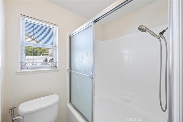 bathroom featuring combined bath / shower with glass door and toilet