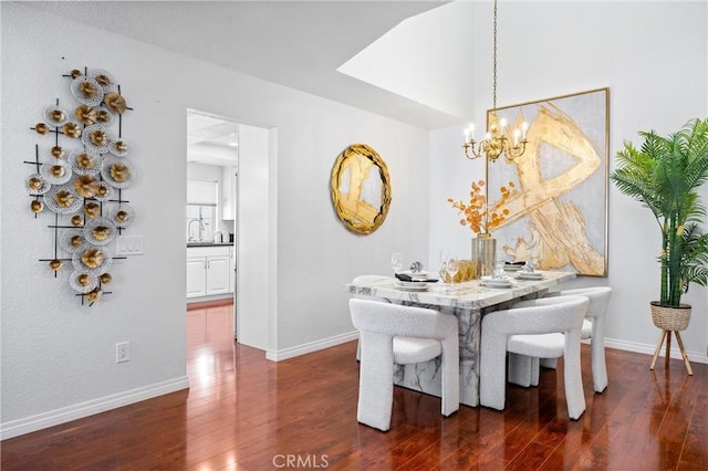 dining area featuring sink, dark wood-type flooring, and a chandelier