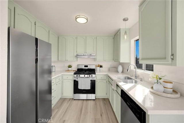 kitchen featuring decorative light fixtures, sink, green cabinets, stainless steel appliances, and light wood-type flooring