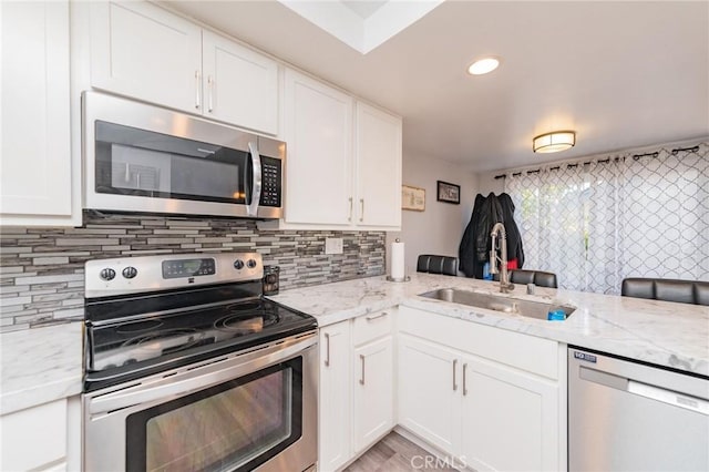 kitchen featuring stainless steel appliances, sink, white cabinets, and kitchen peninsula