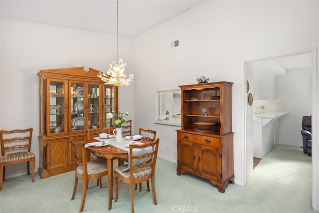 dining space featuring light carpet and an inviting chandelier