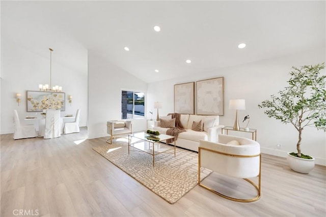 living room with an inviting chandelier, light hardwood / wood-style flooring, and high vaulted ceiling