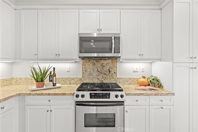 kitchen with light stone counters, backsplash, stainless steel appliances, and white cabinets